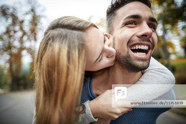 Fröhliches junges Paar küsst sich im Freien