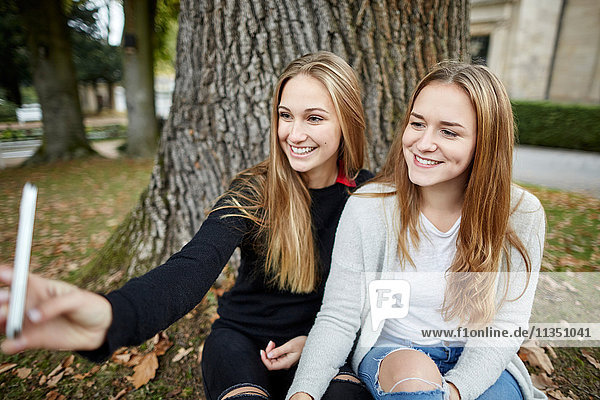 Zwei lächelnde junge Frauen machen ein Selfie im Freien