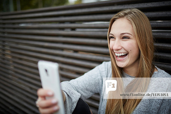 Fröhliche junge Frau mit Handy im Freien
