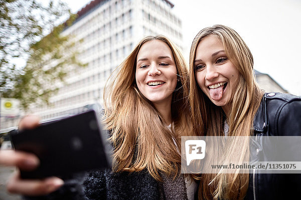 Two playful young women taking a selfie outdoors