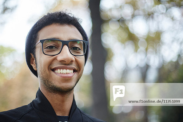 Portrait eines lächelnden jungen Mannes mit Brille im Freien