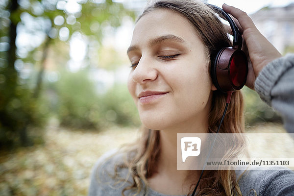 Young woman with closed eyes wearing headphones