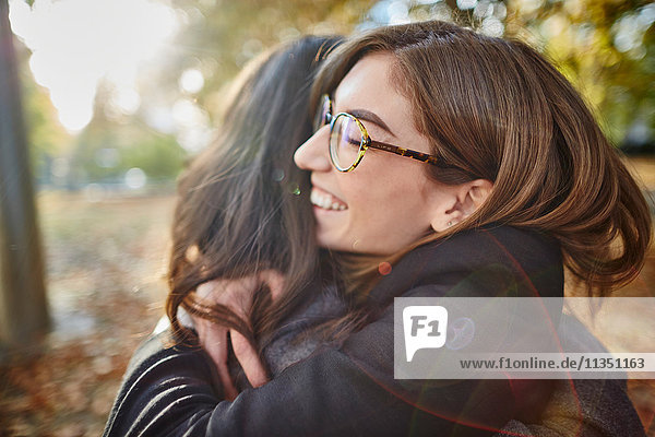 Zwei lächelnde Frauen umarmen sich im Park
