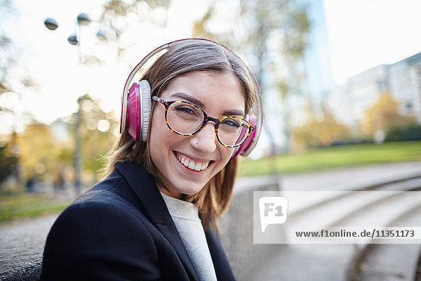 Portrait of happy woman wearing headphones outdoors