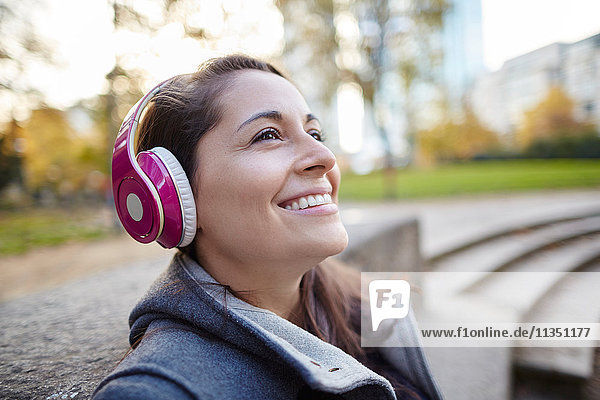 Lächelnde Frau mit Kopfhörern im Freien