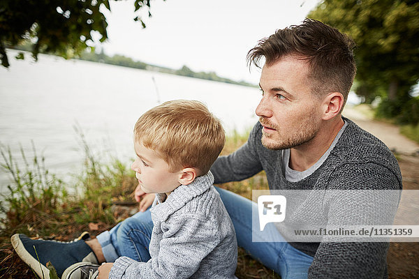 Vater und Sohn sitzen am Flussufer