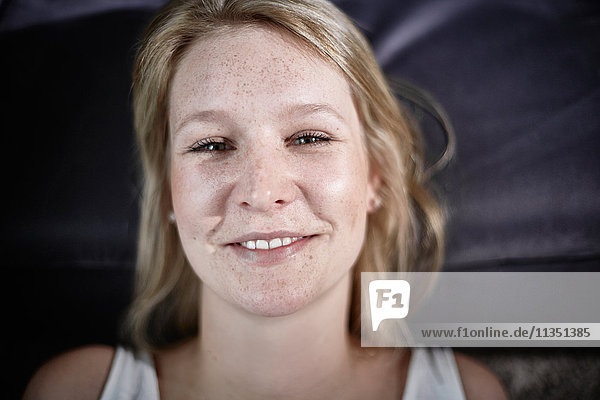Portrait einer lächelnden jungen Frau mit Sommersprossen