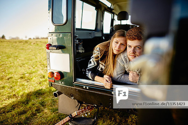 Young couple lying in car parked on meadow