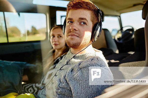 Relaxed young couple inside car with headphones