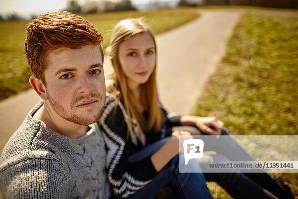 Junges Paar sitzt an einem Feldweg