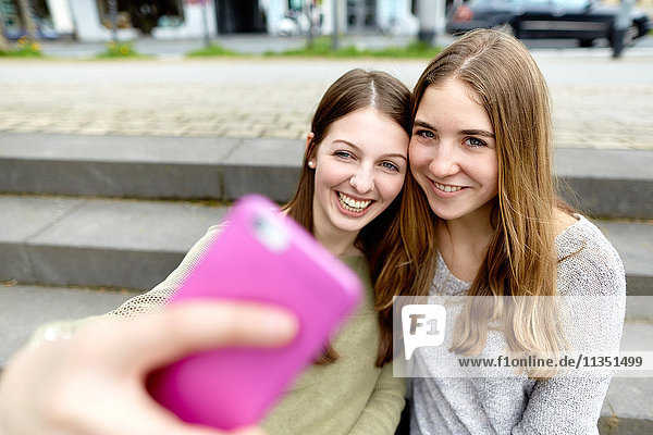 Zwei lächelnde junge Frauen machen ein Selfie