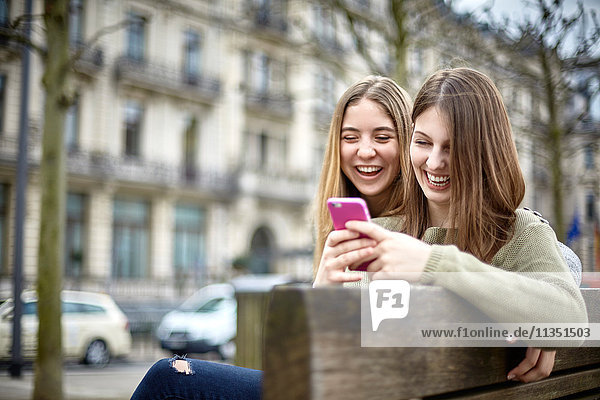 Two happy young women with cell phone