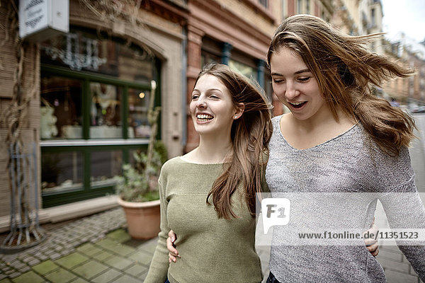 Two happy young women strolling in the city