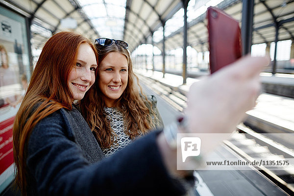 Zwei junge Frauen machen ein Selfie auf dem Bahnsteig