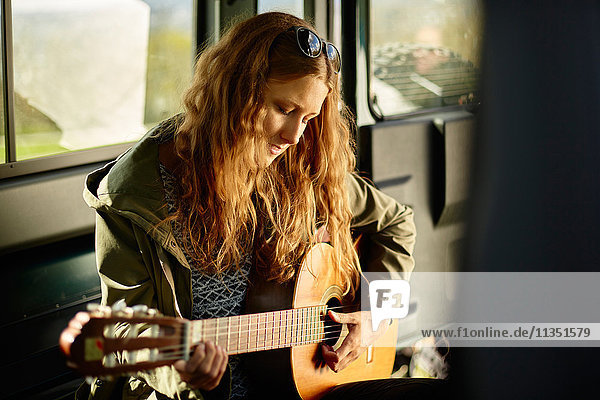 Junge Frau spielt Gitarre im Auto