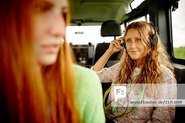 Young woman in car with headphones and paper streamers