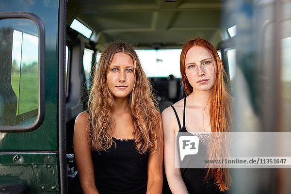 Two young women sitting in trunk of off-road vehicle