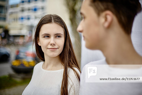 Lächelnde Teenagerin schaut auf Jungen im Freien