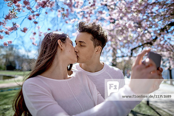 Teenage couple in love kissing and taking a selfie