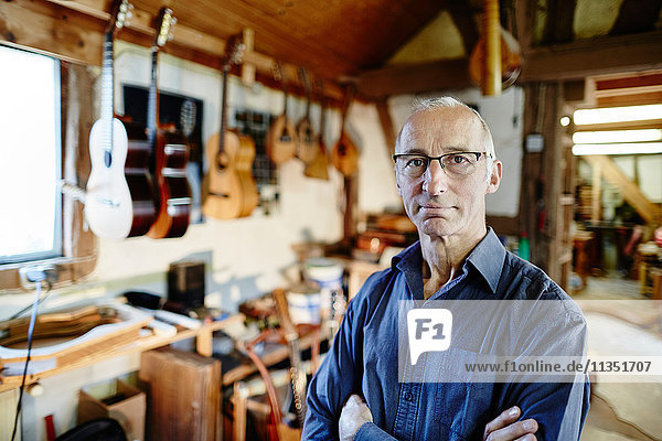 Portrait eines zuversichtlichen Gitarrenbauers in seiner Werkstatt