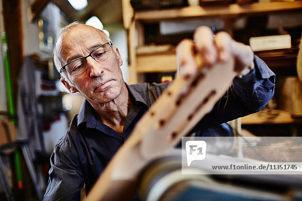 Guitar maker grinding fingerboard in his workshop