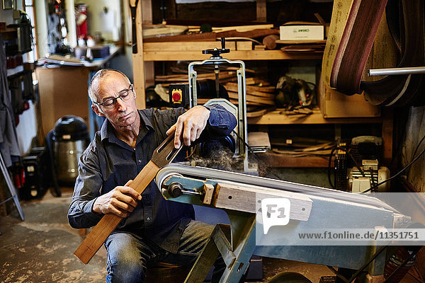 Guitar maker grinding fingerboard in his workshop
