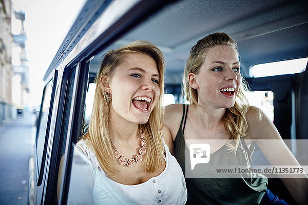 Zwei fröhliche junge Frauen im Auto singen