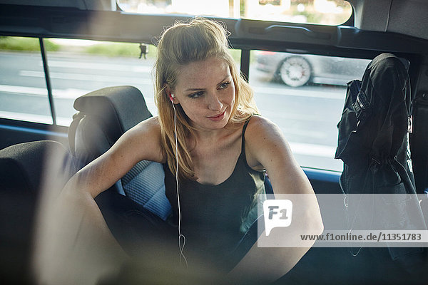 Young woman in car with earbud