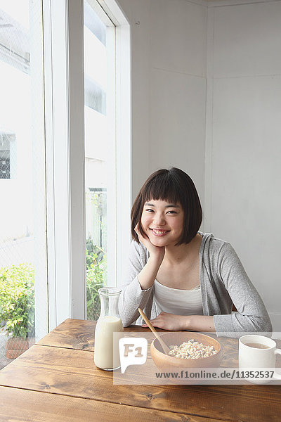 Young Japanese woman having breakfast in airy room