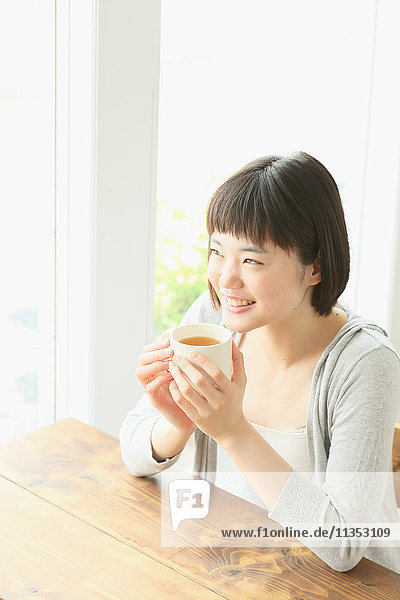 Young Japanese woman drinking in airy room