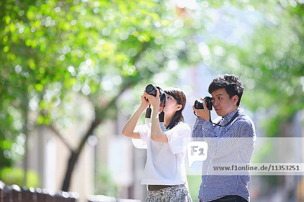 Young Japanese people taking pictures in city park