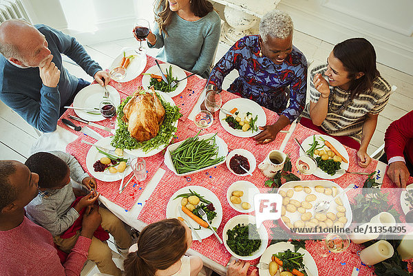 Overhead view multi-ethnic multi-generation family enjoying Christmas dinner at table