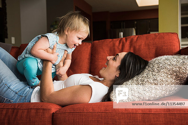 Mother playing with daughter on sofa