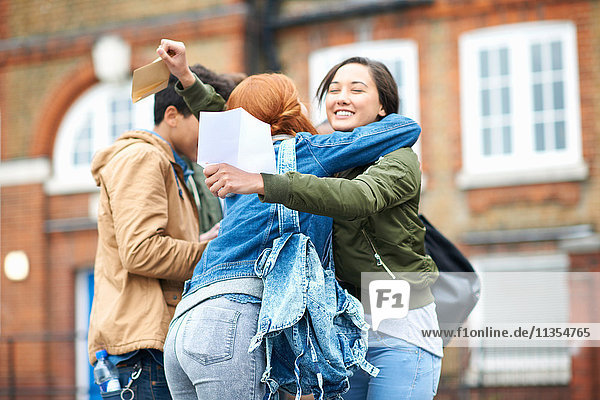 Junge erwachsene College-Studenten gratulieren sich gegenseitig zu ihren Prüfungsergebnissen auf dem Campus