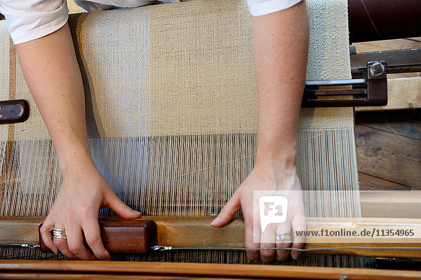 Hands of young woman using loom