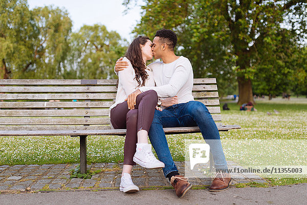 Young couple on park bench kissing