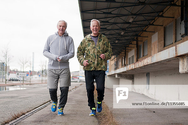 Ältere Freunde in Sportkleidung beim Joggen nebeneinander