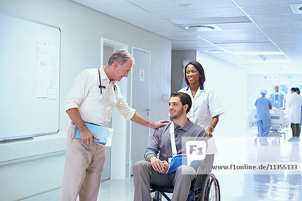 Doctor consulting with man in wheelchair with arm sling
