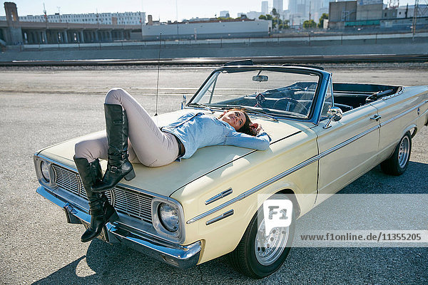Woman lying on convertible car bonnet  Los Angeles  California  USA