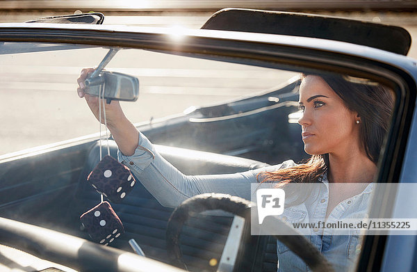 Woman in convertible car adjusting rear view mirror  Los Angeles  California  USA