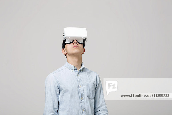Junger Mann mit Virtual-Reality-Kopfhörer schaut auf