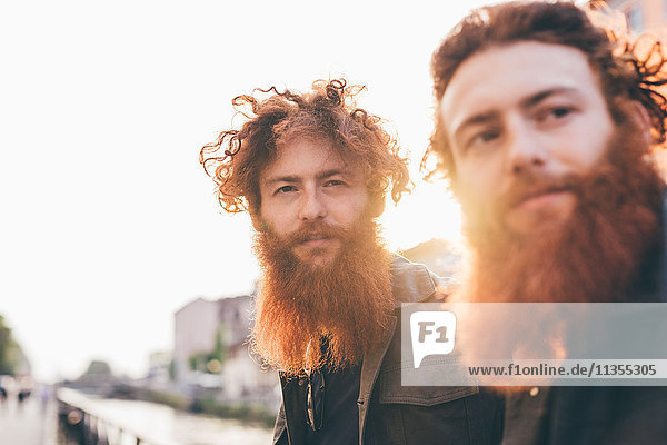 Junge männliche Hipster-Zwillinge mit roten Haaren und Bärten am Kanalufer