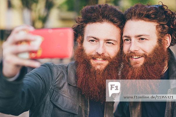 Junge männliche Hipster-Zwillinge mit roten Haaren und Bärten nehmen Smartphone Selfie