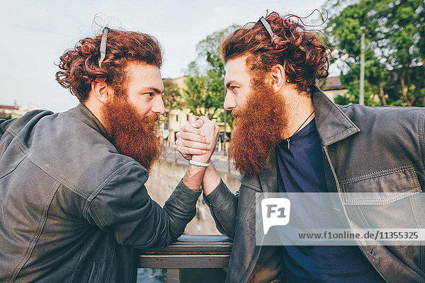 Junge männliche Hipster-Zwillinge mit roten Haaren und Bärte Armdrücken auf Brücke