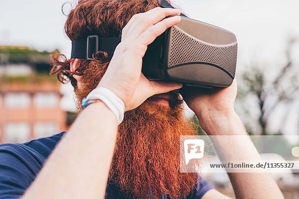 Junger männlicher Hipster mit roten Haaren und Bart im Virtual Reality Headset