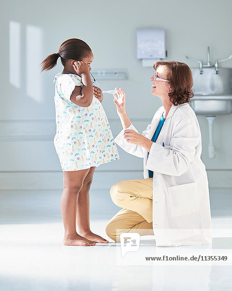 Girl listening to doctors stethoscope in hospital children's ward