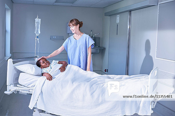 Krankenschwester  die eine Patientin im Bett auf der Kinderstation des Krankenhauses betreut