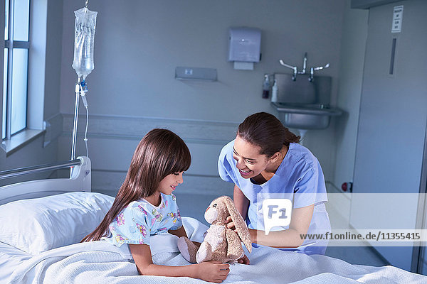 Krankenschwester und Patientin spielen mit Spielzeugkaninchen auf der Kinderstation des Krankenhauses