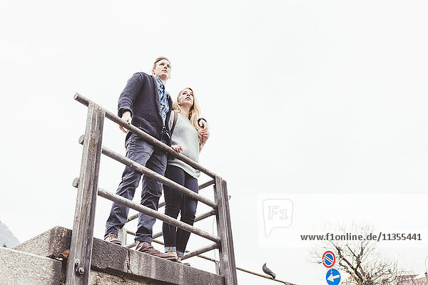 Low angle view of young couple looking out from harbour wall  Lake Como  Italy