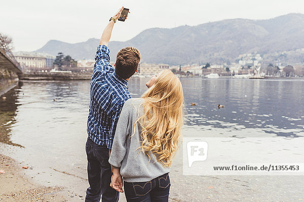 Young couple taking smartphone selfie on lakeside  Lake Como  Italy